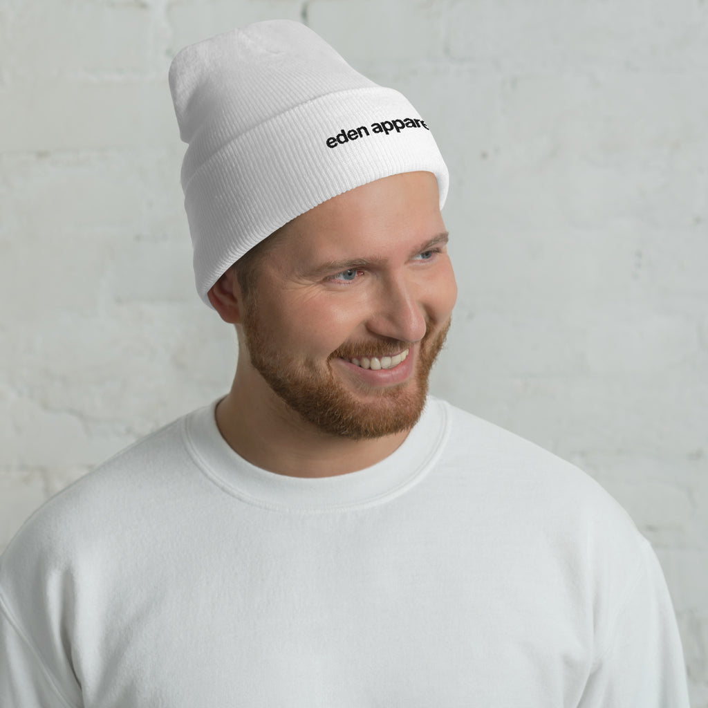 Man wearing a white beanie with 'eden apparel' logo against a light gray background